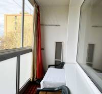 Glazed loggia in a 3-room apartment with a table and a plastic chair.