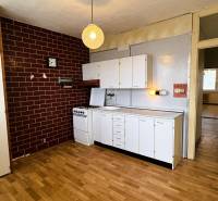 A kitchen in a 3-room apartment with white cabinets and a wood-patterned floor.