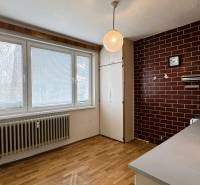 A kitchen with a wooden decor floor in a 3-room apartment with brown tiles.