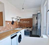 A kitchen in a 3-room apartment with a wood-patterned floor and appliances.