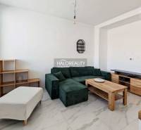 Living room with a dark sofa in a 3-room apartment with tiled flooring and wooden decor furniture.