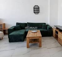 Living room in a three-room apartment with a green sofa and a wooden table.