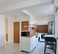 A kitchen in a 3-room apartment with white cabinets, appliances, and wooden decor.