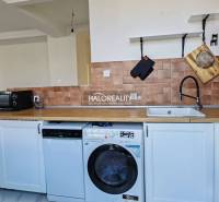 A kitchen in a 3-room apartment with white cabinets, tiles, and a wood-patterned floor.