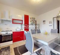 A family house kitchen with red cabinets, a dining table, and a wood-patterned floor.