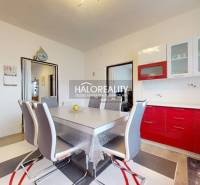 A dining room with a red kitchen unit and a wooden decor floor in a family house.