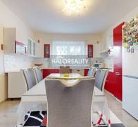 A kitchen in a family house with a red kitchen unit and a dining table.