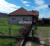 A family house in Rimavské Janovce on a plot with green lawn and fencing.