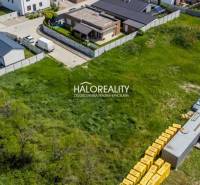 A view of a housing estate in Senec with vacant plots for housing, surrounded by buildings and roads.