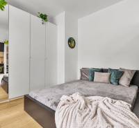 A bedroom in a studio apartment with a bed, a white wardrobe, and a wooden floor.