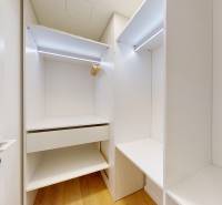 Built-in wardrobe with a light interior and a floor with wood decor in a studio apartment.