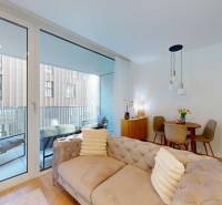 Living space in a one-room apartment with a balcony, sofa, and kitchen table.
