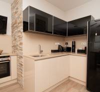 A kitchen in a 2-room apartment with stone cladding and a wooden decor floor.