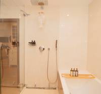 A bathroom with a bathtub, shower, and minimalist design in a 2-room apartment.