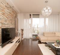 Living room in a two-room apartment with a stone wall and a wooden decor floor.
