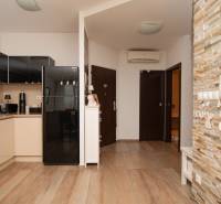 A kitchen in a 2-room apartment with a wooden decor floor and stone wall cladding.