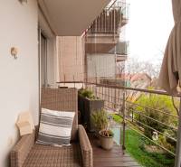 A balcony with a rattan chair and plants in a 2-room apartment.
