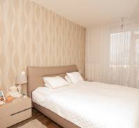 A bedroom in a two-room apartment with beige wallpaper and a wooden decor floor.