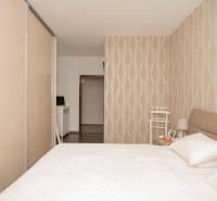 A bedroom in a 2-room apartment with wallpaper and a wardrobe in cream shades.