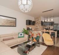 Living room with a beige sofa, chimney cladding column, and wooden decor flooring.