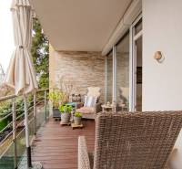 A balcony with a wooden decor floor and wicker furniture in a 2-room apartment.