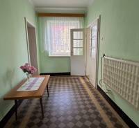 A hallway in a family house with flowers on the table and a tiled floor.