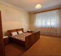 Bed with armchair and nightstands in a home bedroom with carpet.