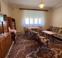 Living room in a family house with a carpet, furniture, and a chandelier, curtains on the windows.