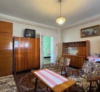 Living room in a family house with a carpet, older furniture, and a chandelier.