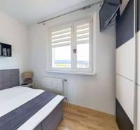 A bedroom with a bed and a television, a floor with a wooden decor in a three-room apartment.