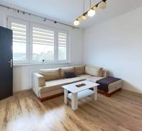 Living room with a sofa and wood-patterned flooring in a three-room apartment.