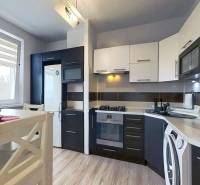 A kitchen in a 3-room apartment with a kitchen unit and appliances, flooring with a wooden decor.