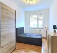 Bright bedroom in a three-room apartment with wood-patterned flooring and a large wardrobe.