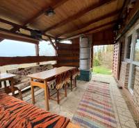 A cottage in Žilina with wooden seating, a fireplace, and a view of nature.