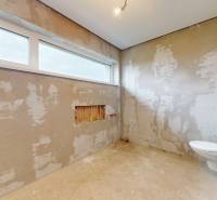 Unplastered bathroom with a large window and sanitary equipment in a family house.