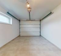 A garage in a family house with a large entrance gate and a window on the side wall.