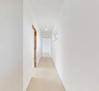 A white hallway in a family house with an unfinished floor and smooth walls.