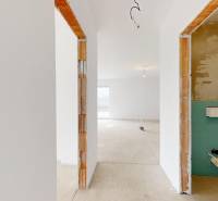 In the construction of a family house, there is a bright room with plastered walls and a concrete floor.