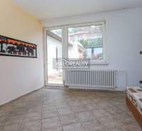 Interior of a family house with a tiled floor, a sofa, and a large window.