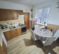A kitchen in a family house with wooden decor, with a dining table and kitchen unit.
