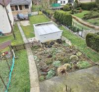 A family house in Horné Ozorovce, Bánovce nad Bebravou, features a garden with a flower bed and a garage.