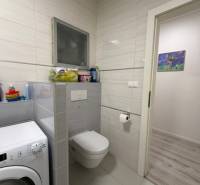 Bathroom with a washing machine, toilet, and tiles in a 2-room apartment.