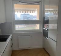 A kitchen with a wooden decor floor in a 2-room apartment has modern appliances.