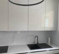 A kitchen with white cabinets and a marble countertop in a 2-room apartment.