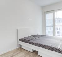Bright bedroom with a bed and wood-decorated flooring in a 2-room apartment.