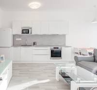 A bright kitchen with white cabinets and a sofa in a two-room apartment.