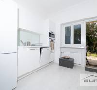 A kitchen with white cabinets and access to the terrace in a 4-room apartment.