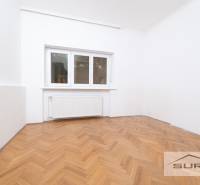 A room in a 4-room apartment with white walls and a wooden decor floor.