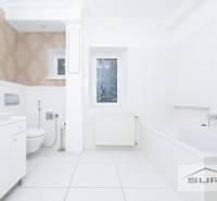 A bathroom with a shower and a bathtub in a 4-room apartment, white tiles, patterned wallpaper.