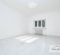 An empty room with white walls and a wooden-patterned floor in a 4-room apartment.